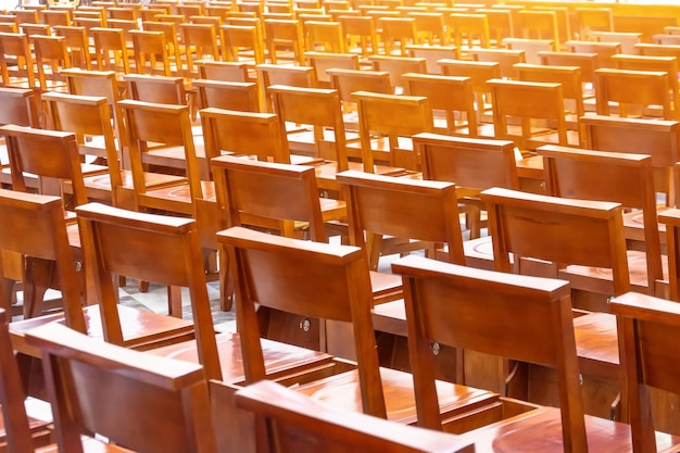 Chaises dans l'église dans la salle de prière fauteuils marron en bois en rangées derrière