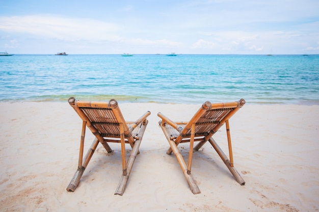 Chaises longues blanches sur une belle plage tropicale aux Maldives