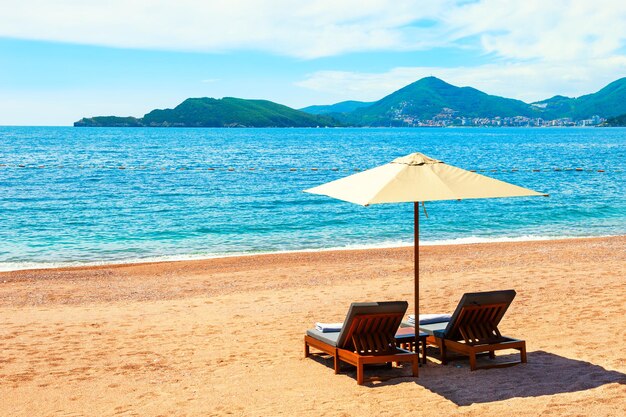 Chaises longues sur la plage de sable. Belle côte maritime près de Budva, Monténégro.