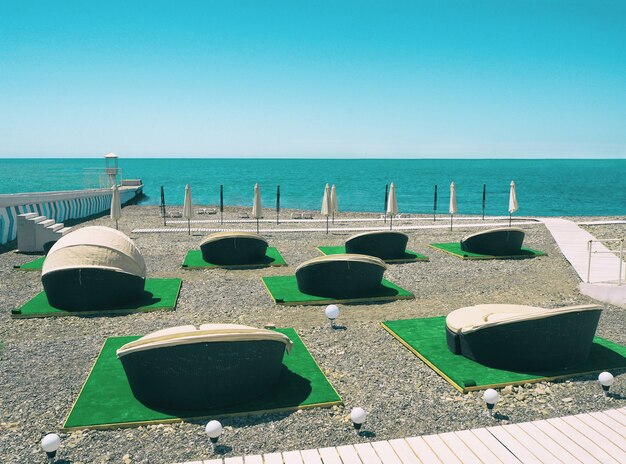 Chaises longues en plein air ou chaises longues de patio sur la plage au fond bleu de la mer et du ciel