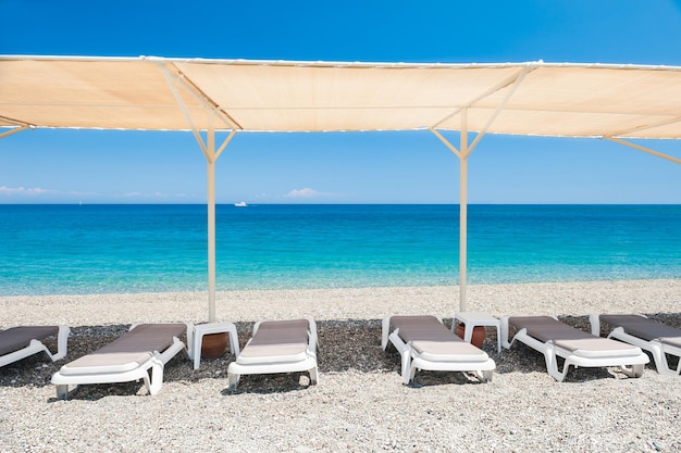 Chaises longues sous la tente sur la plage de galets à Kemer, Turquie. Concept de voyage et de vacances