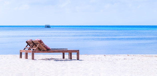 Chaises sur la magnifique plage de sable près de l'océan avec un ciel bleu.