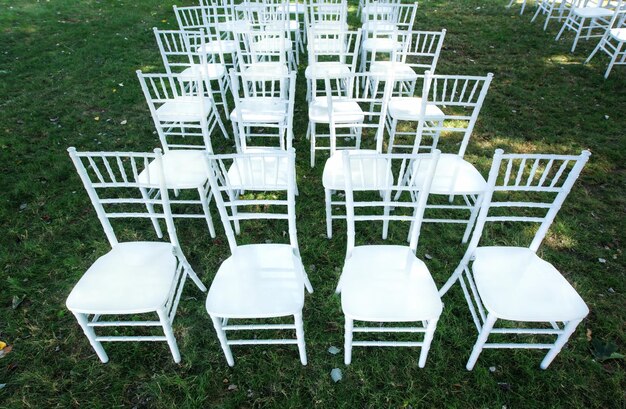 Chaises de mariage blanches classiques sur une pelouse verte sans décoration Été