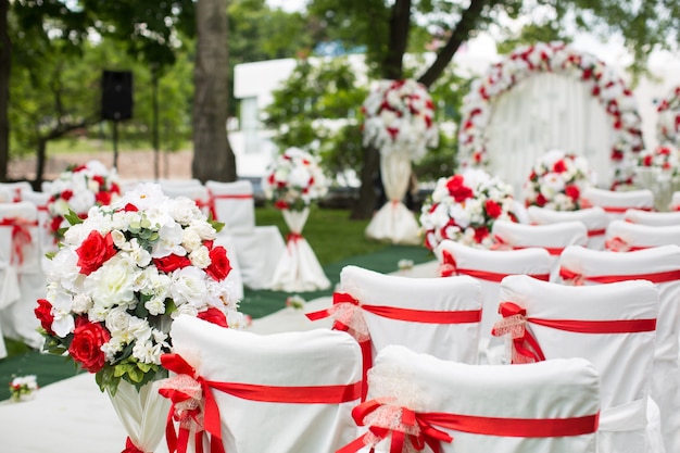 Chaises de mariage blanches avec des rubans rouges