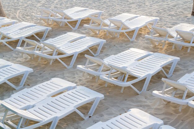 Chaises de piscine blanches sur la plage.