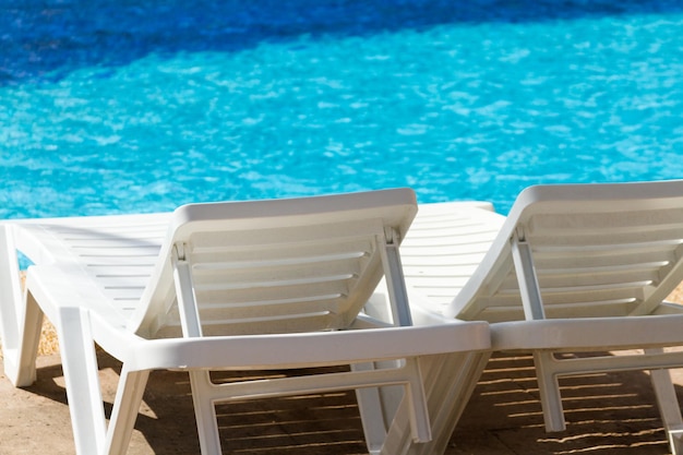 Chaises de piscine en plastique blanc à la piscine.