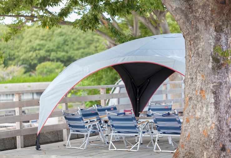 Photo des chaises pliantes et une table sous un arbre dans un terrain de camping