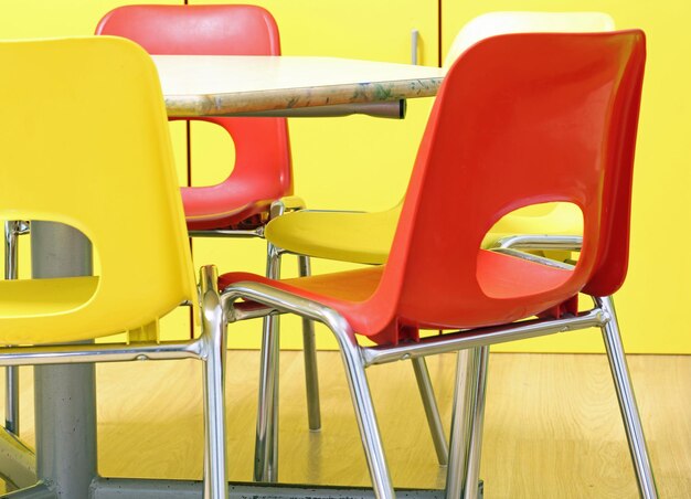 Photo des chaises rouges et jaunes dans la salle de classe d'une école maternelle sans enfants