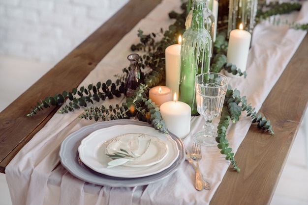 chaises et table pour les invités, décorées de bougies, servies avec couverts et vaisselle et recouvertes d'une nappe.