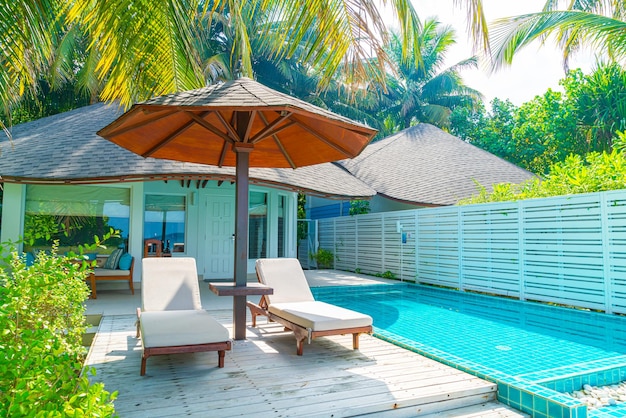 Des chaises et des tables près de la piscine contre les arbres