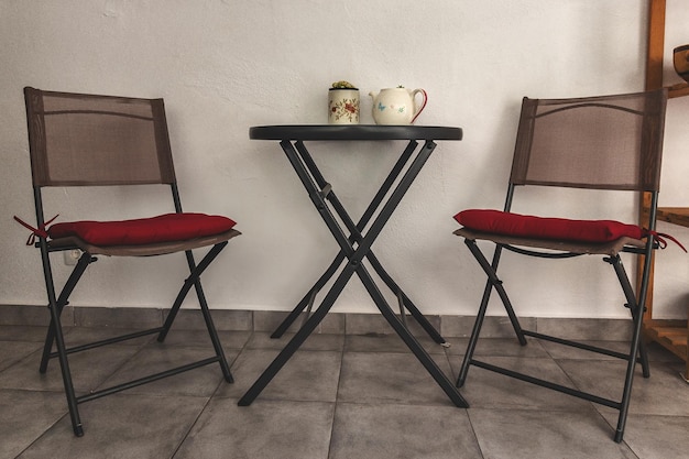 Photo des chaises et des tables vides contre le mur à la maison.