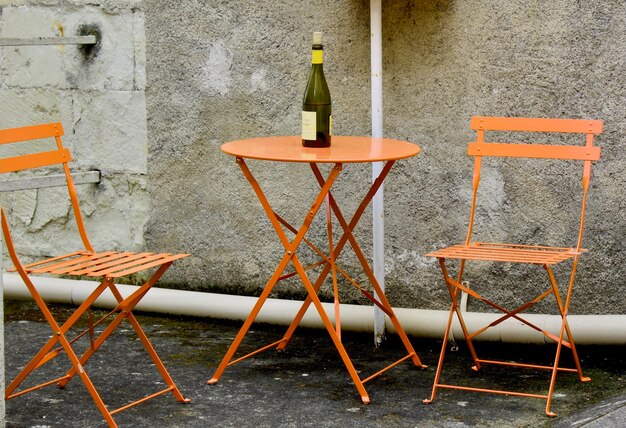 Photo des chaises et des tables vides dans un café sur le trottoir contre le mur.