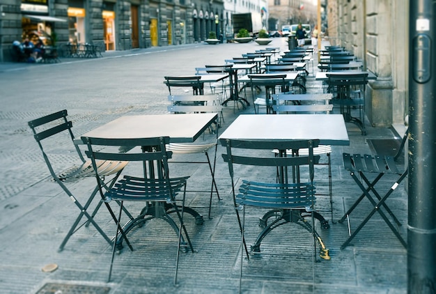 Photo des chaises et des tables vides dans un café sur le trottoir.