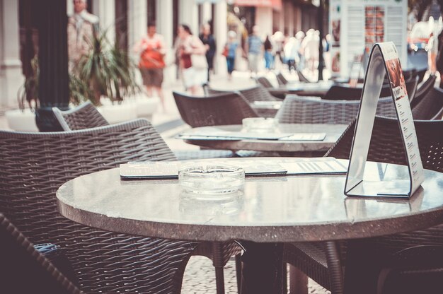 Des chaises et des tables vides disposées dans un café sur le trottoir.