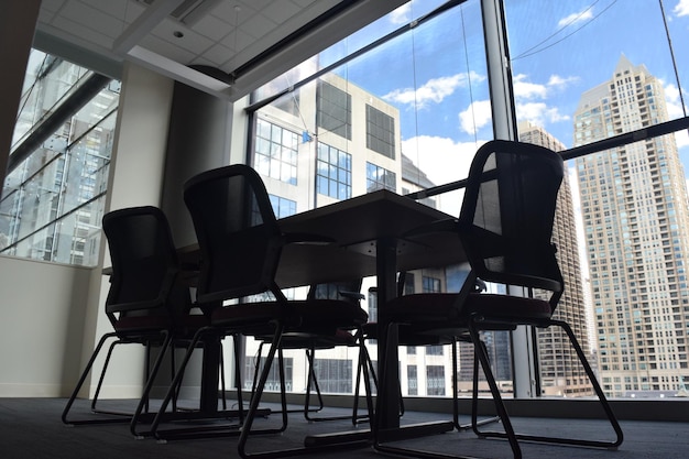 Des chaises et des tables vides près d'une fenêtre de verre dans le bâtiment