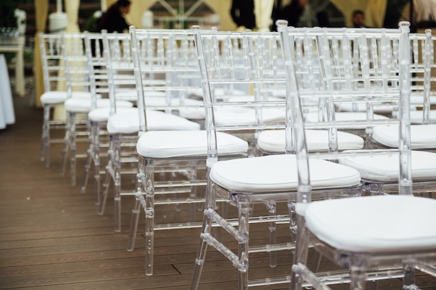 Des chaises en verre se tiennent dans une rangée lors d'une belle cérémonie de sortie de mariage