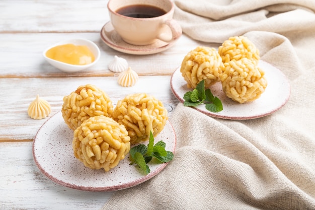 Chak-chak de bonbons tatare traditionnel fait de pâte et de miel avec une tasse de café sur un fond en bois blanc et textile en lin. Vue de côté, gros plan.