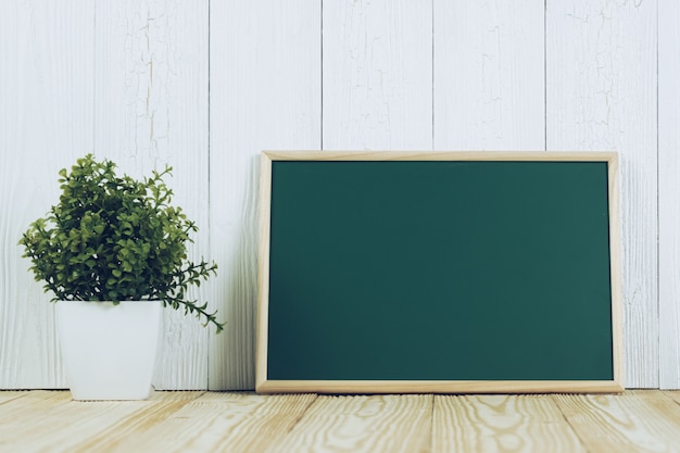 Chalkborad verte blanche avec cadre en bois et petit arbre sur bois