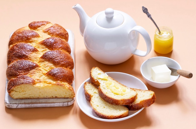 Challah à base de pâte à levure avec théière et pain sur fond orange clair