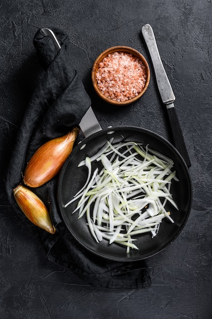 Échalote tranchée dans une poêle, cuisson des oignons frits. Vue de dessus