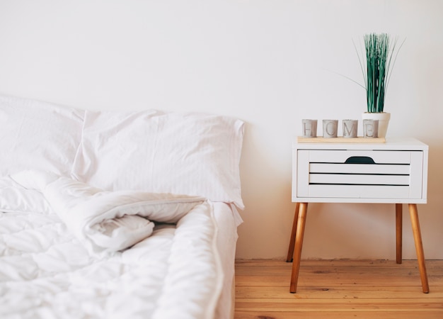 Chambre confortable de couleur blanche avec table de chevet