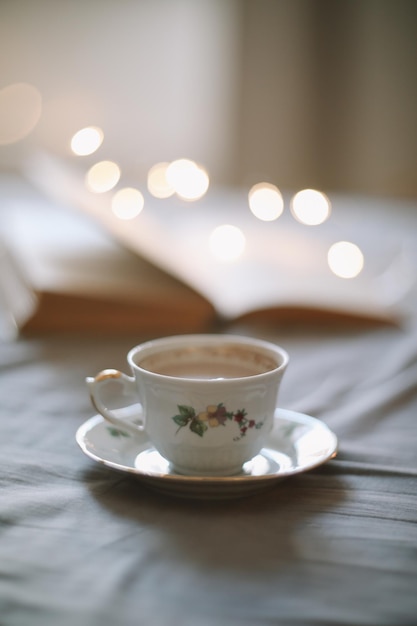 Chambre confortable et lumineuse Tasse de café ou de thé et un livre ouvert sur le lit Nature morte printanière Petit-déjeuner au lit