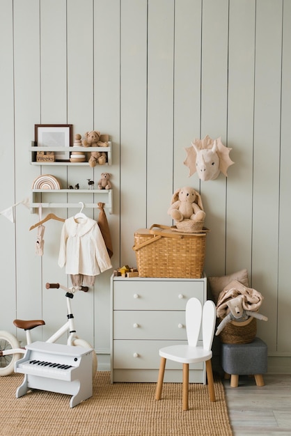 Chambre d'enfant de style scandinave commode vélo jouets piano jouet fauteuil et vêtements sur cintre