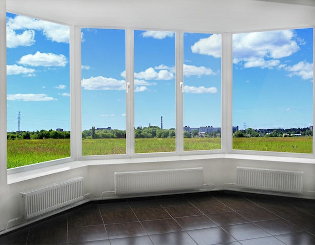 chambre avec une fenêtre intérieure moderne sur le champ d'été et une vue sur les tubes de la ville