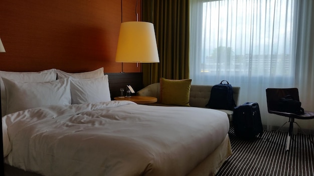 Une chambre d'hôtel de luxe avec une lumière chaleureuse, un lit et un canapé est prête à accueillir ses invités.