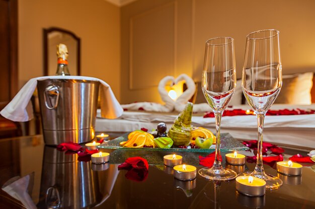 Chambre d'hôtel pour une lune de miel: une table avec une assiette de fruits et des bougies