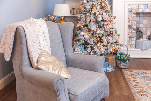 Chambre intérieure décorée de Noël classique, arbre du nouvel an avec des décorations en argent. Appartement de design d'intérieur de style classique bleu moderne avec cheminée et fauteuil. Le réveillon de Noël à la maison.