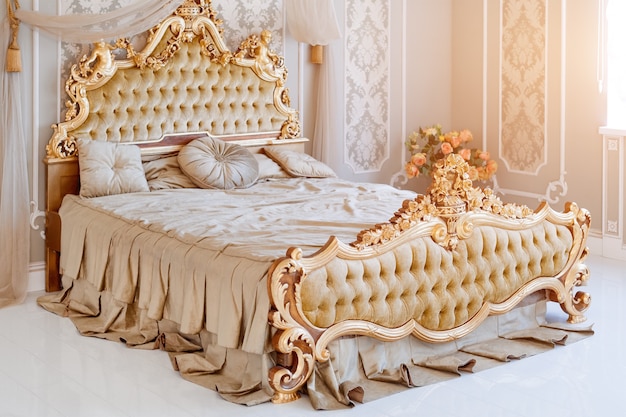 Chambre de luxe aux couleurs claires avec des détails de meubles dorés