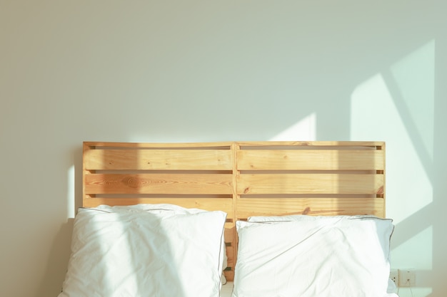 Chambre mezzanine avec lit blanc au soleil doux du matin d'hiver.