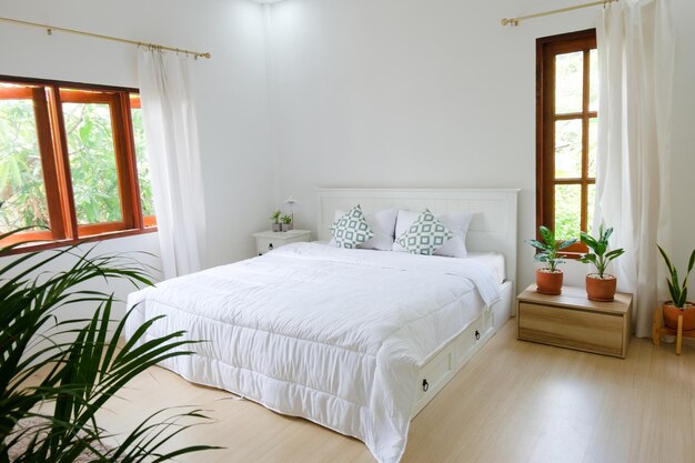 Chambre minimaliste avec lit blanc au sol en bois et plantes