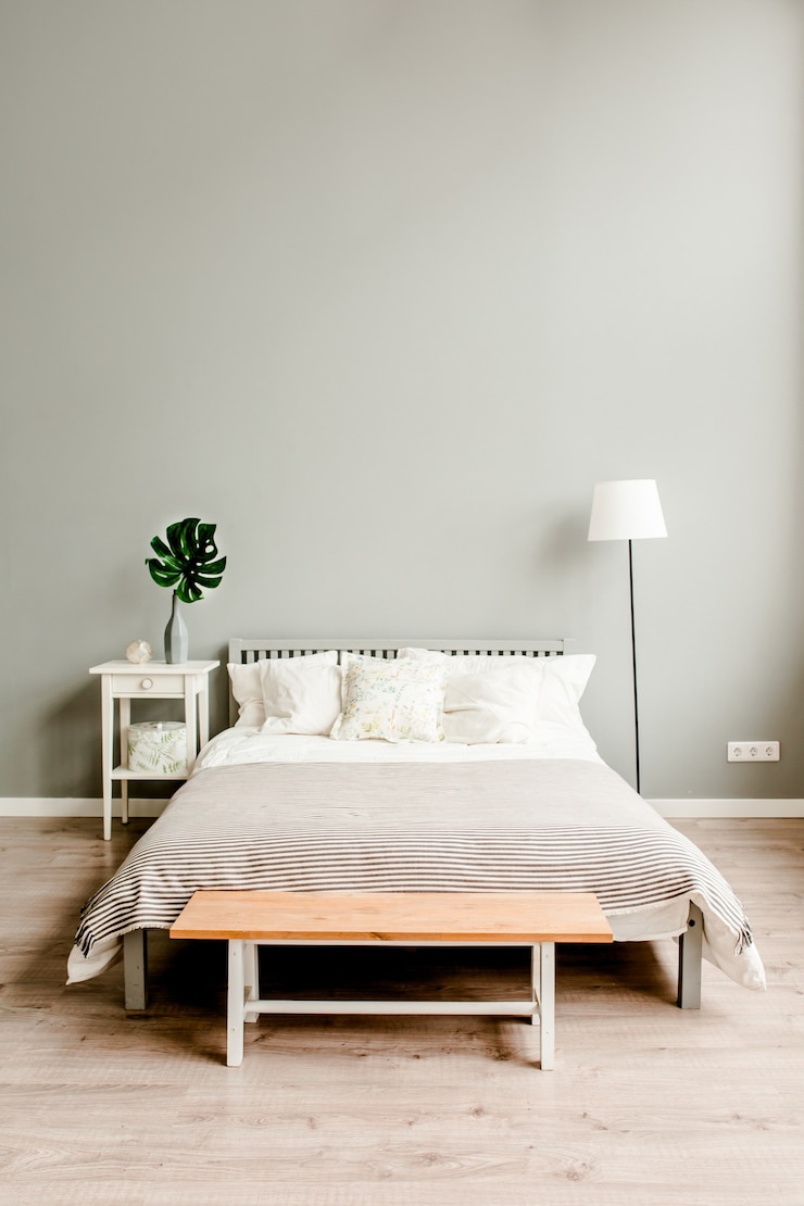 Photo chambre avec mobilier en bois de style scandinave et plante monstera sur une table de chevet tronc d'arbre
