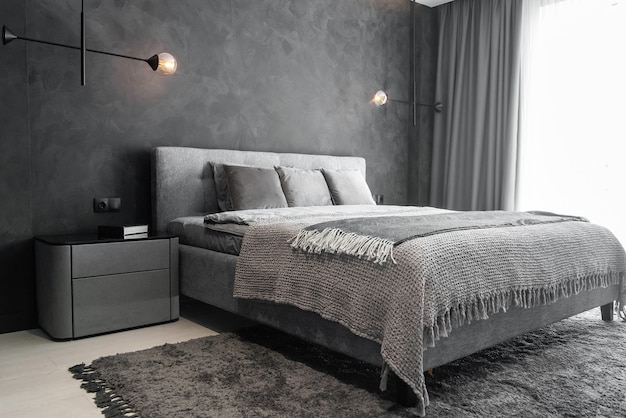 Chambre moderne avec des intérieurs gris tendance, un grand lit king-size et des lampes