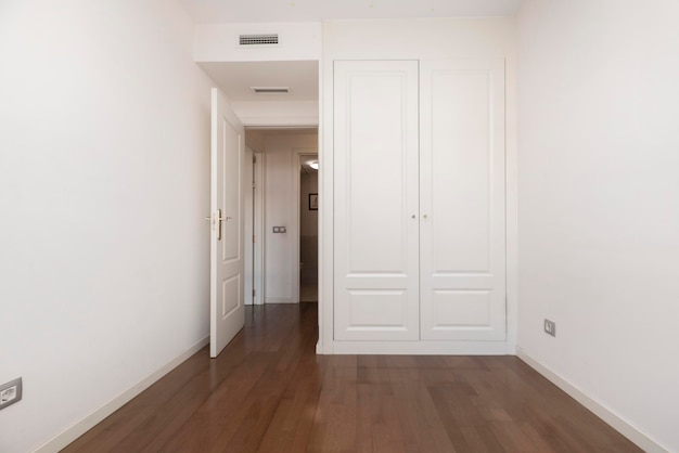 Chambre avec parquet sombre, placards avec portes en bois laqué blanc et climatisation par conduits internes