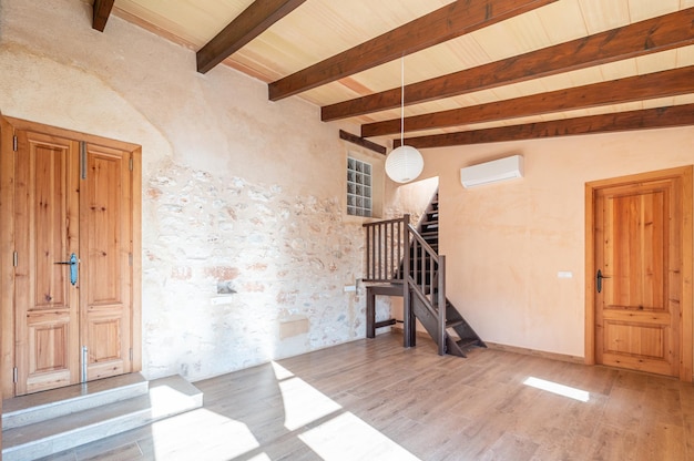 Chambre principale vide à aire ouverte avec parquet, poutres en bois, balcon et climatisation en ru