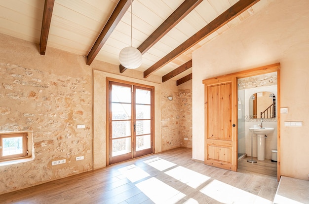 Chambre principale vide à aire ouverte avec parquet, poutres en bois, balcon et climatisation