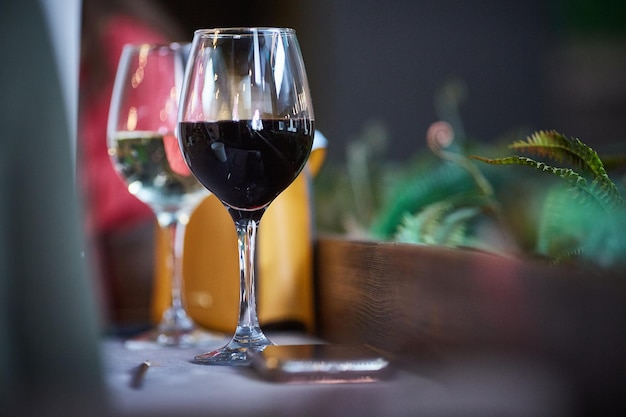 Chambre romantique avec verres à vin dans un intérieur de luxe Deux verres de vin avec du vin rouge et blanc sont sur la table dans la chambre avec des fleurs Espace de copie