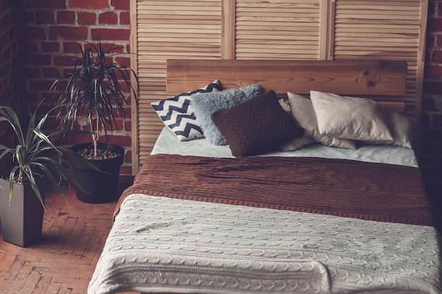 Chambre simple avec lit double, mur de briques rouges et grande fenêtre