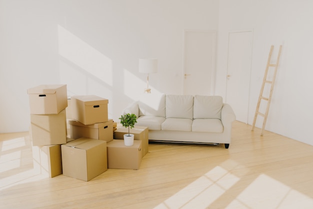 Chambre spacieuse avec canapé, piles de cartons et échelle