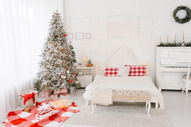 Chambre spacieuse et lumineuse de style loft dans des tons blancs et rouges avec un sapin de Noël décoré