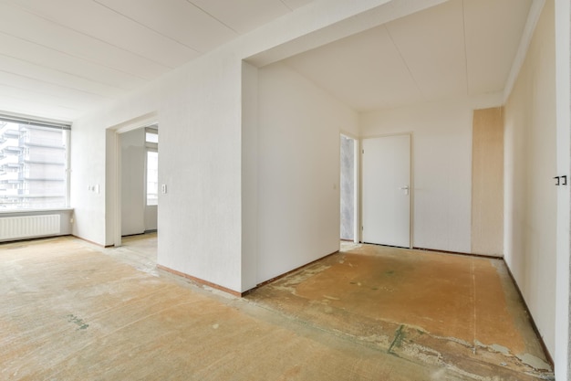 Une chambre spacieuse vide avec de grandes fenêtres et des murs blancs dans un appartement d'un immeuble résidentiel