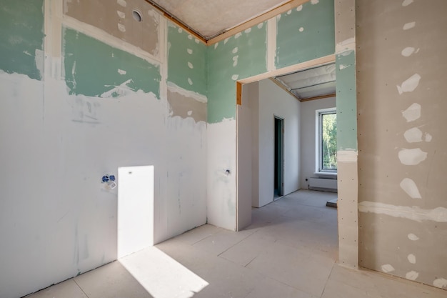 Chambre vide non meublée avec un minimum de réparations préparatoires à l'intérieur avec des murs blancs et des cloisons sèches