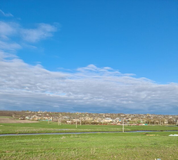 Un champ avec un champ vert et un ciel bleu avec des nuages