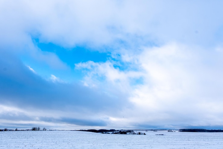 Photo un champ enneigé à l'horizon et un ciel bleu avec des nuages blancs