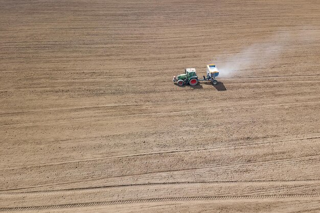 Champ de fertilisation du tracteur, vue aérienne. Tracteur épandant des engrais artificiels.