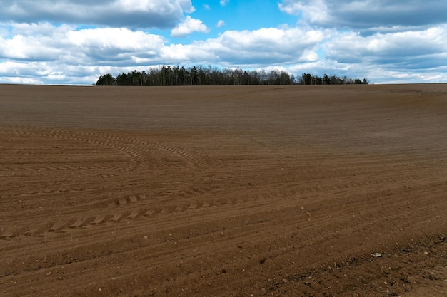 Un champ labouré contre le ciel La saison de plantation des cultures dans un champ de blé La préparation du champ pour la plantation de colza, de blé, de seigle et d'orge dans les zones rurales