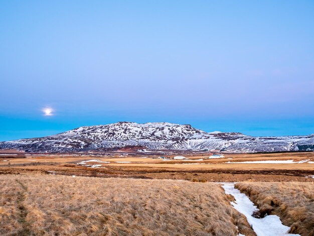 Champ de montagne dans le ciel crépusculaire du soir avec veilleuse de pleine lune en hiver en Islande